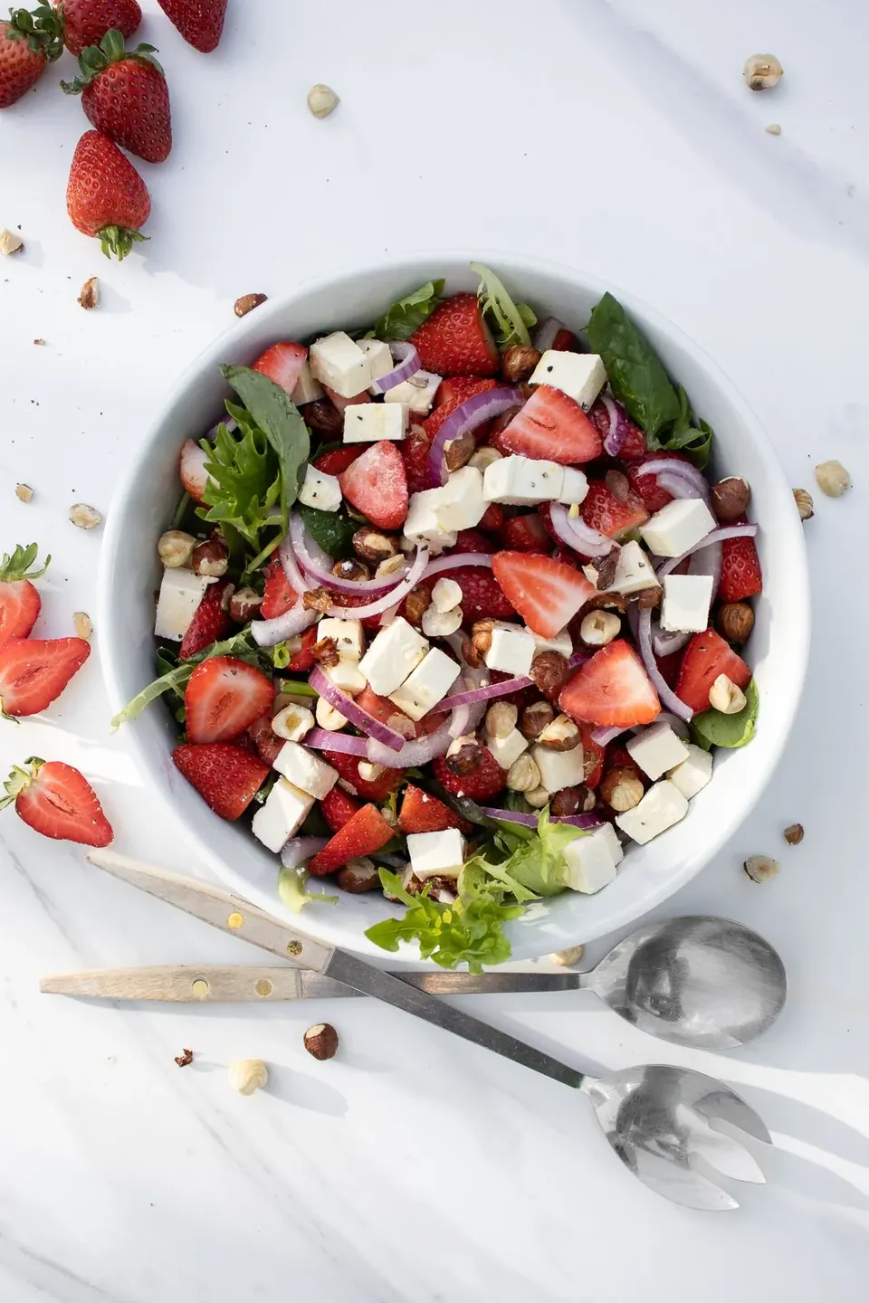 Bowl of strawberry feta salad with hazelnuts and red onion