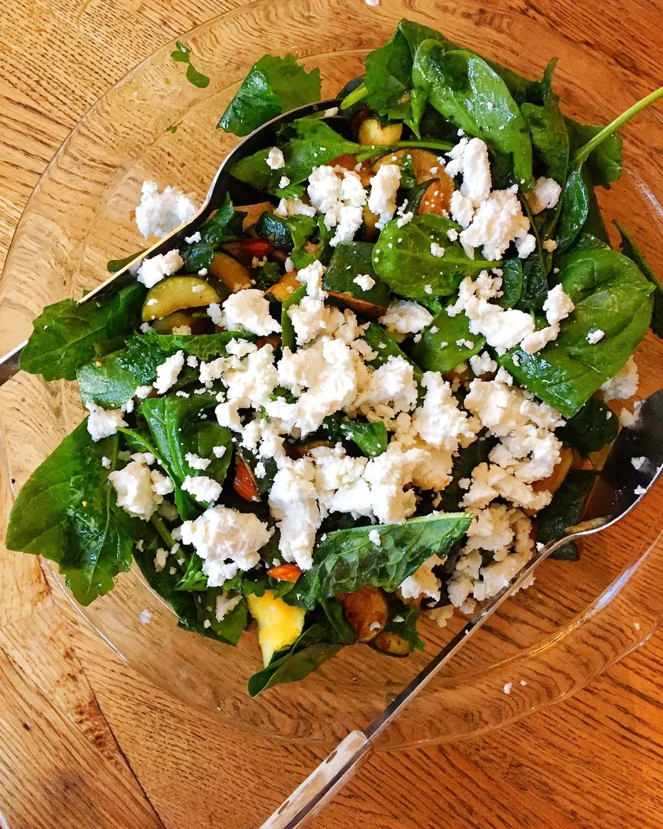 Spinach salad with zucchini, cherry tomatoes, and crumbled goat cheese