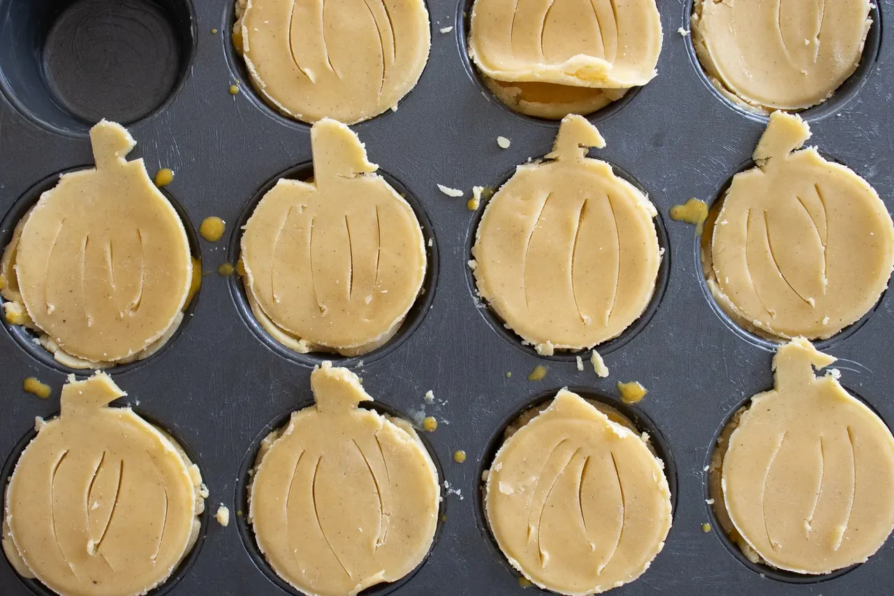 Pumpkin-shaped pie crust tops arranged in a muffin tin